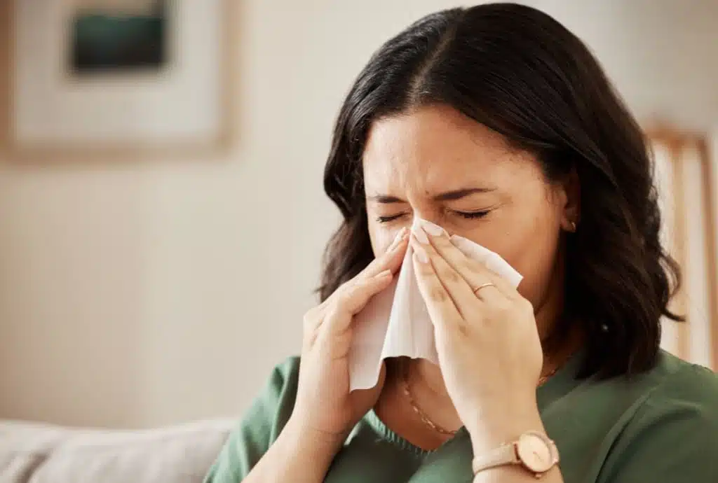Woman with nasal congestion using tissue indoors during allergy season